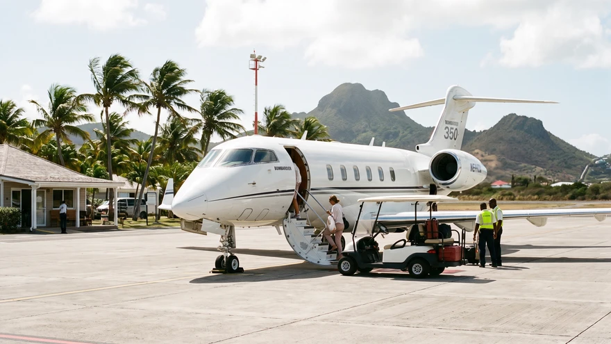 Private jet parked on a tropical airstrip with a golf buggy waiting on the tarmac
