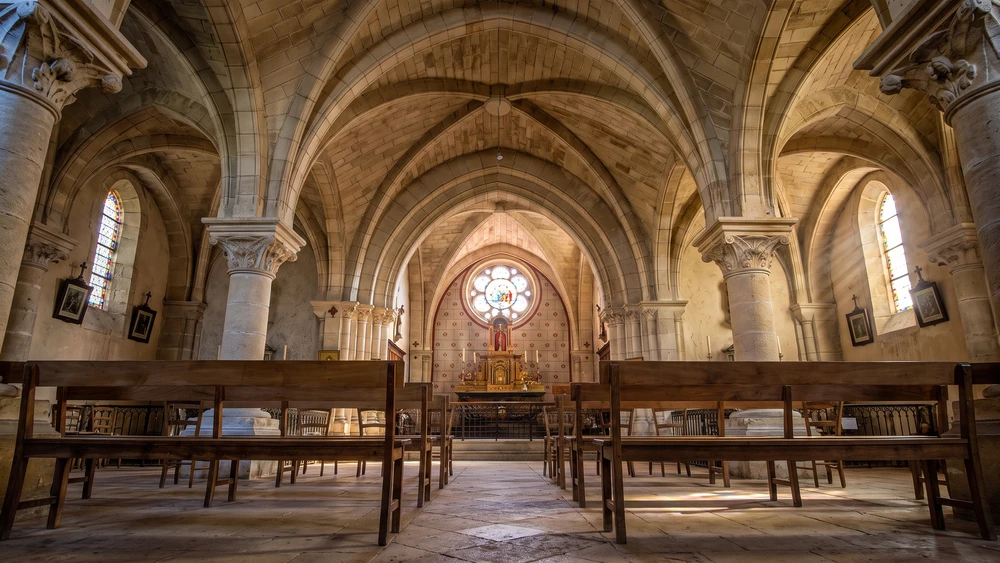 Vaulted stone nave and rose window inside the Church of Notre-Dame in Castelmoron-d'Albret.