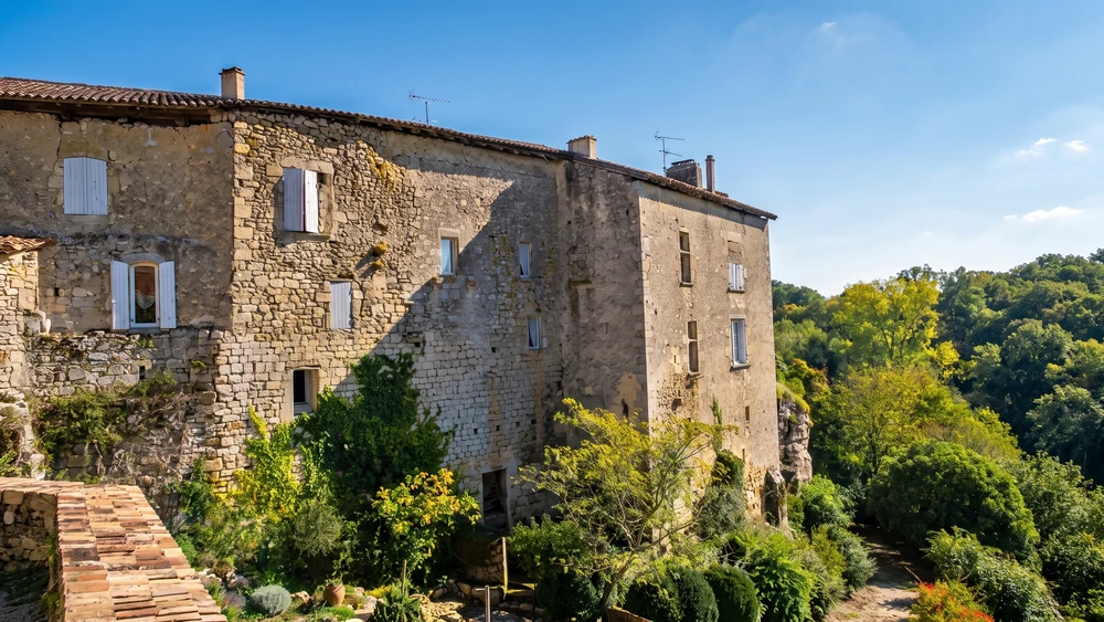 Weathered stone facade of Castelmoron-d'Albret perched above the wooded Entre-deux-Mers valley.