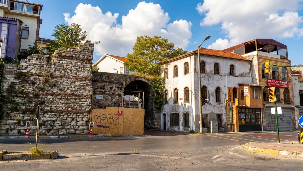 Cibali Gate in Istanbul beside surviving stone walls, a former archway, road, and low historic buildings.