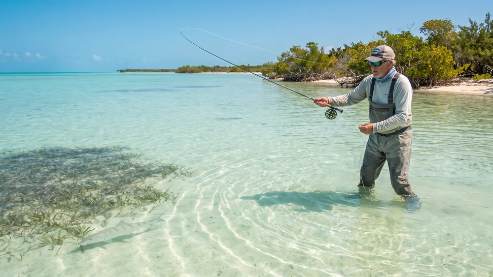Angler fly fishing for bonefish on a shallow lagoon flat