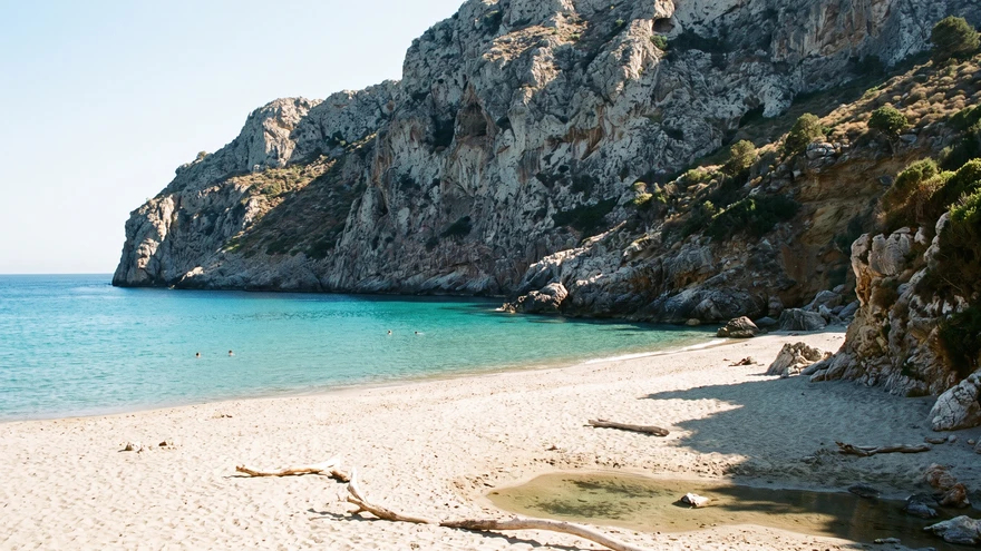 Quiet sandy cove beach with swimmers beneath the cliff face of the Rock