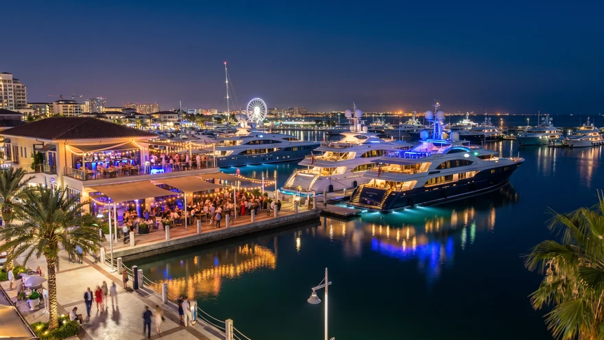 Illuminated marina at Ocean Village with superyachts and waterfront bars at night