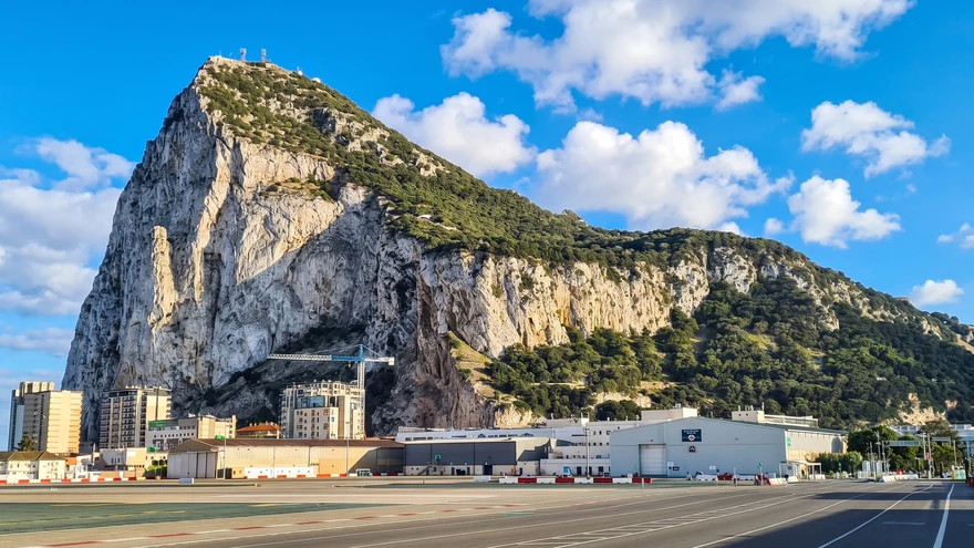Daytime view of the Rock of Gibraltar cliffs and town below under a clear sky