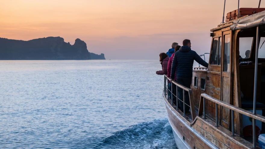 Small tour boat crossing calm strait waters in soft morning light
