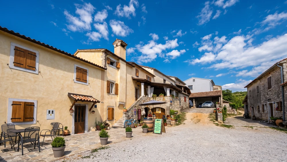 Traditional Istrian farmhouse with wooden shutters and a wine tasting stand in a village near Hum.