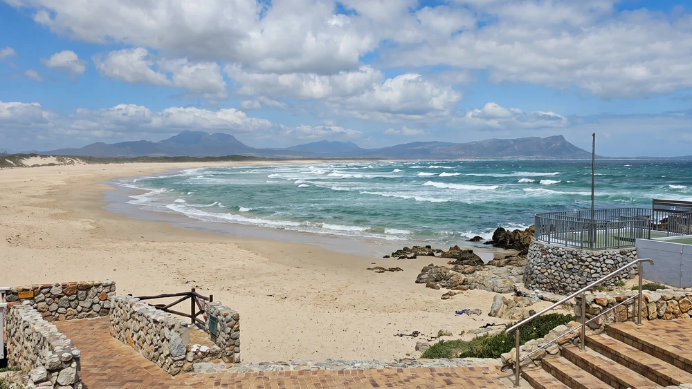 Wide view of Kleinmond beach with waves and distant mountains