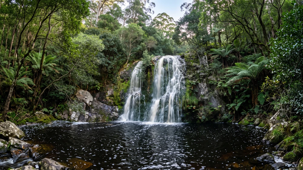 Multi-tiered waterfall cascading into a dark forest pool at the end of the Leopard's Kloof trail