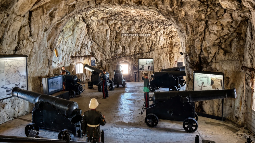 Historic cannons and military mannequins displayed inside the Gunners Gallery of Gibraltar's WWII Tunnels